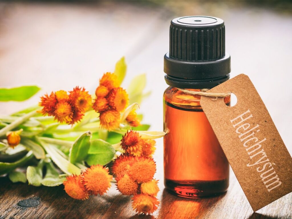 Helichrysum essential oil on a table with name tag and flowers next to it