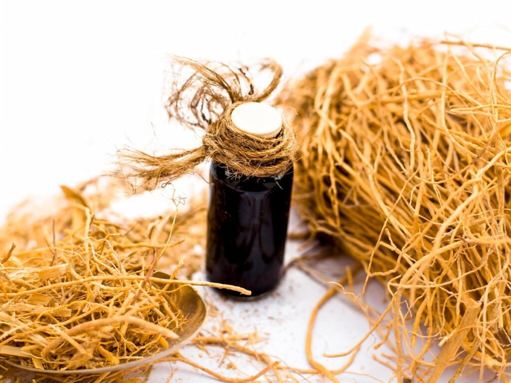 vetiver essential oil on table with roots on table