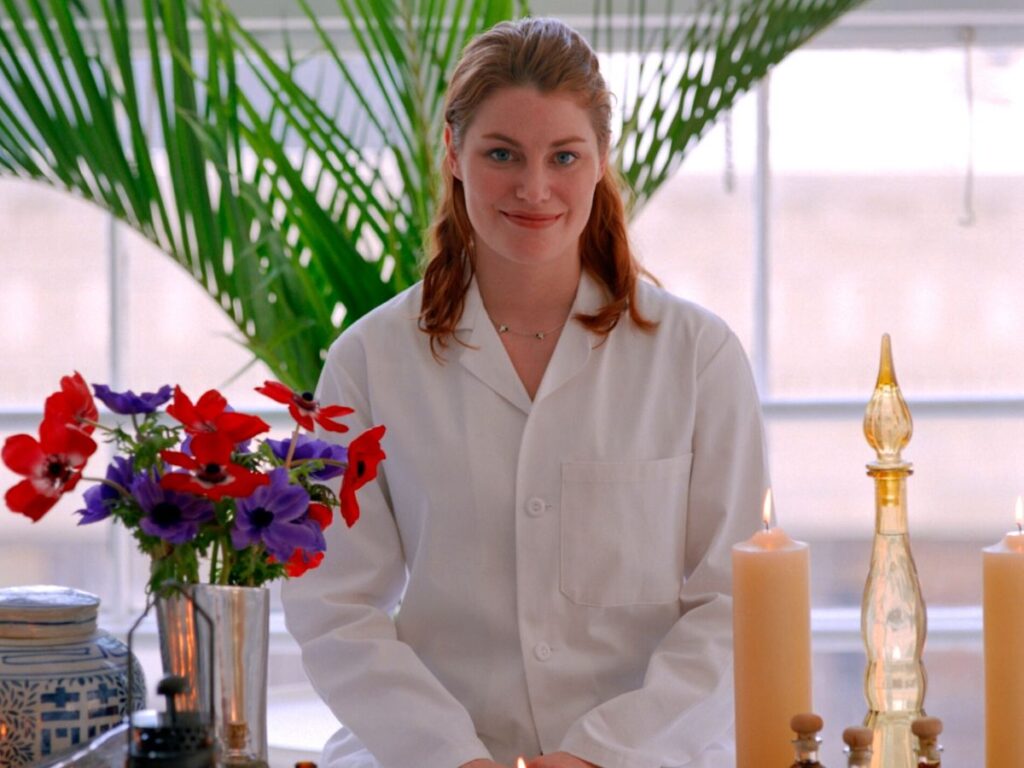 aromatherapist with candles, essential oils and flowers on a table