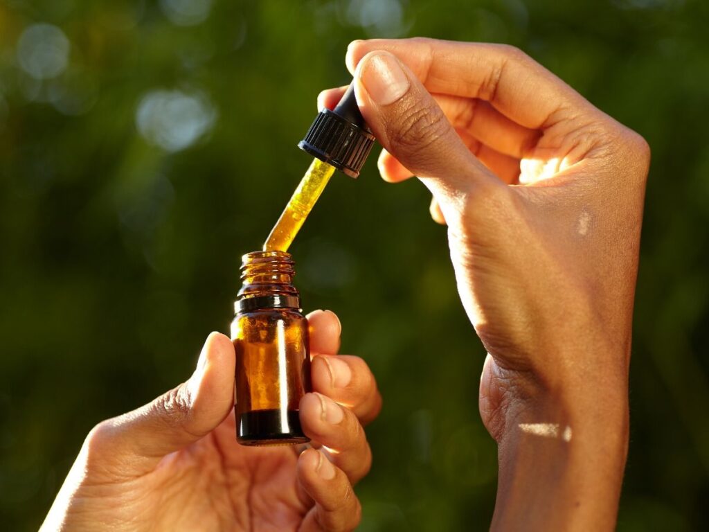 hand holding essential oil dropper over bottle