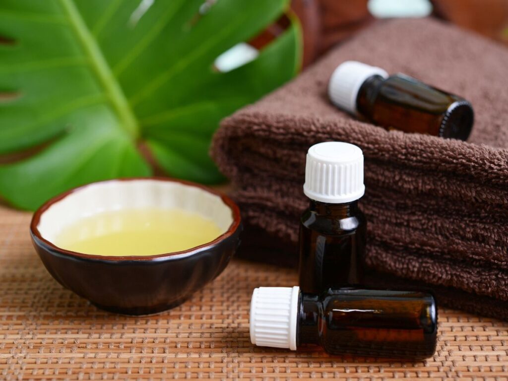 bottles of essential oils with brown towels and a small bowl of carrier oil