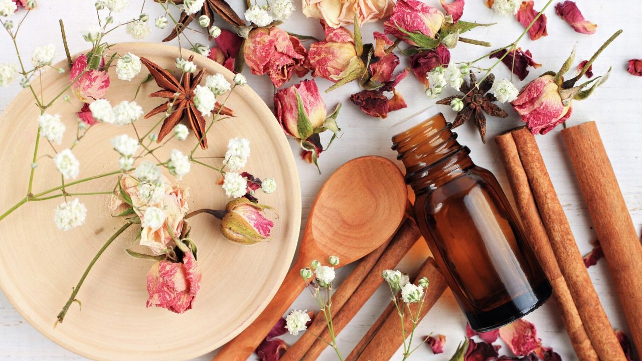 bottle of essential rose oil on table with dried roses.