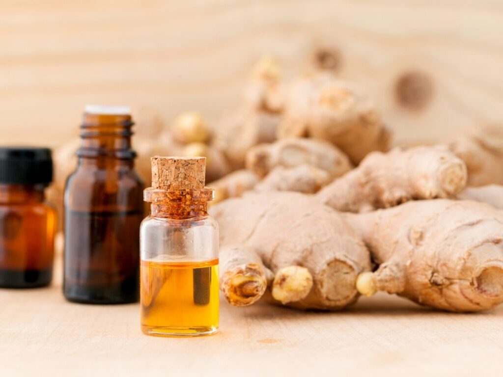 ginger essential oil bottles on table with ginger root in background