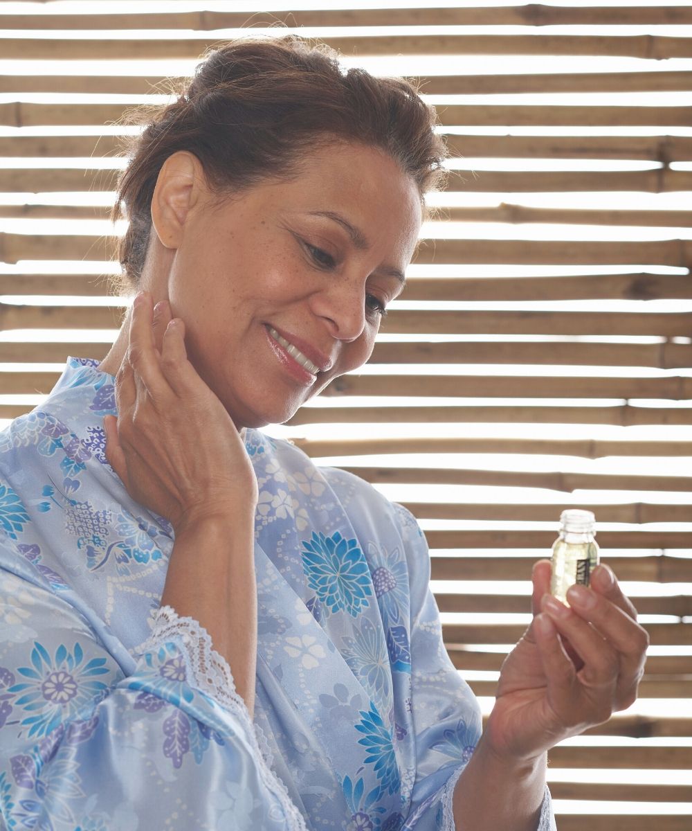 Woman applying essential oil to her neck.