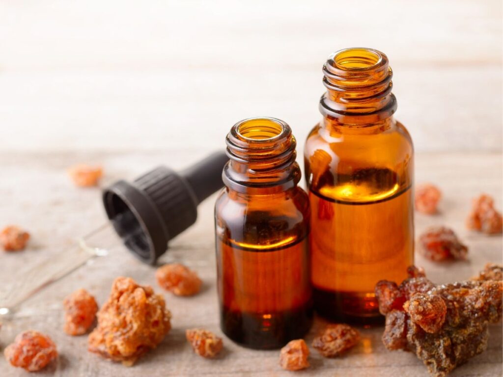 myrrh essential oil in bottles with myrrh on table