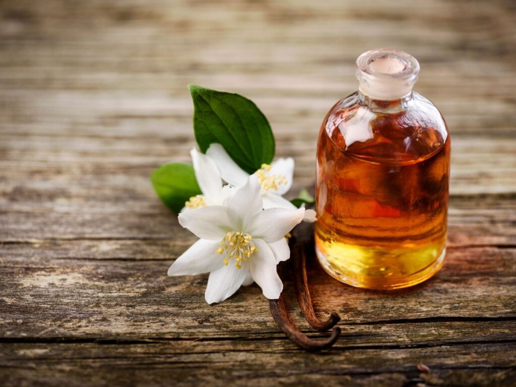 neroli essential oil bottle on table next to white neroli flowers