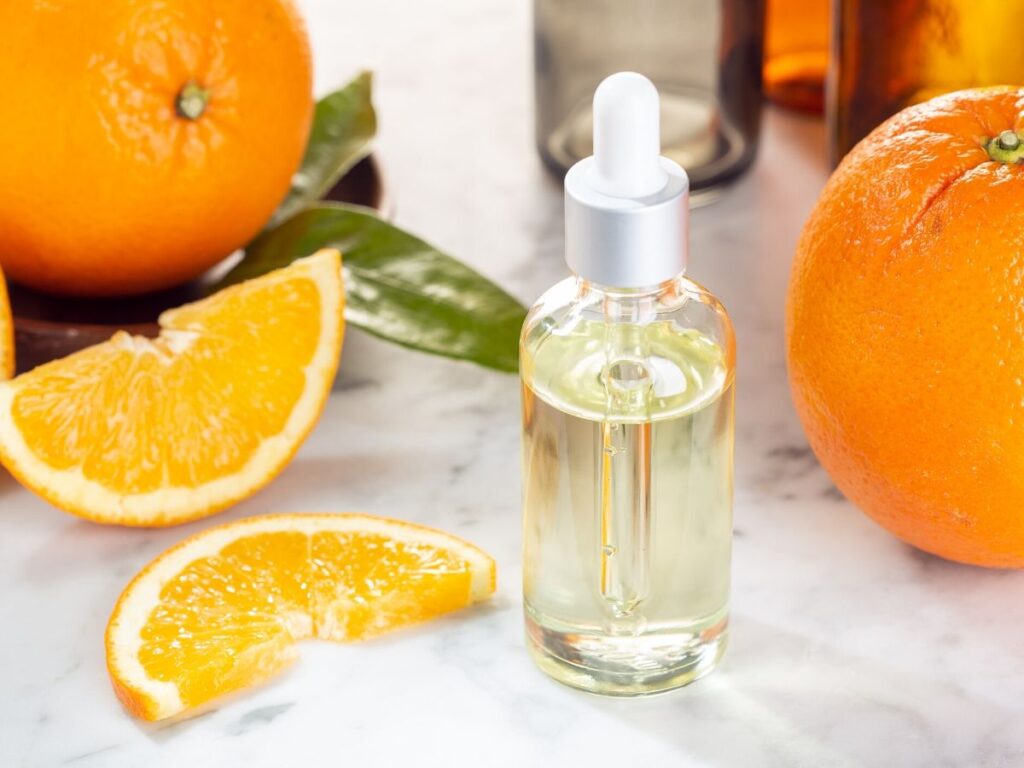 orange slices on table with clear orange essential oil bottle