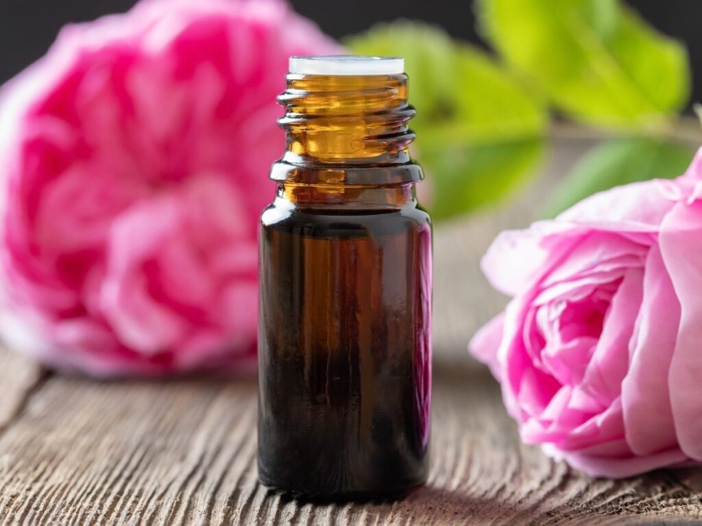 rose essential oil bottle with pink roses on table