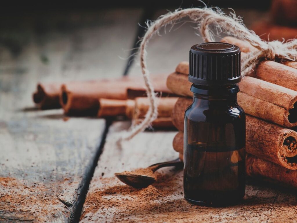 cinnamon essential oil bottle with cinnamon sticks on table.