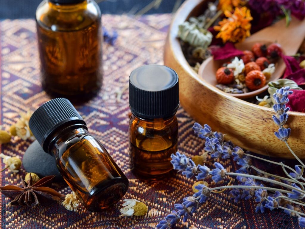 bottles of essential oils with dried flowers on table.