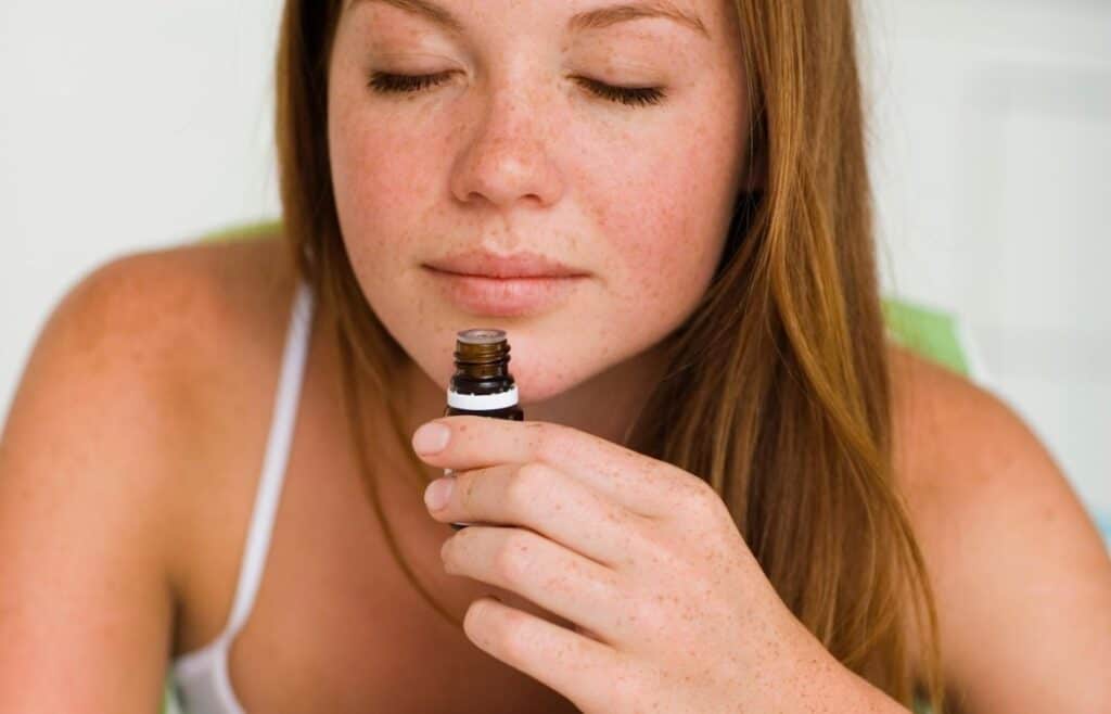 woman inhaling bottle of essential oil