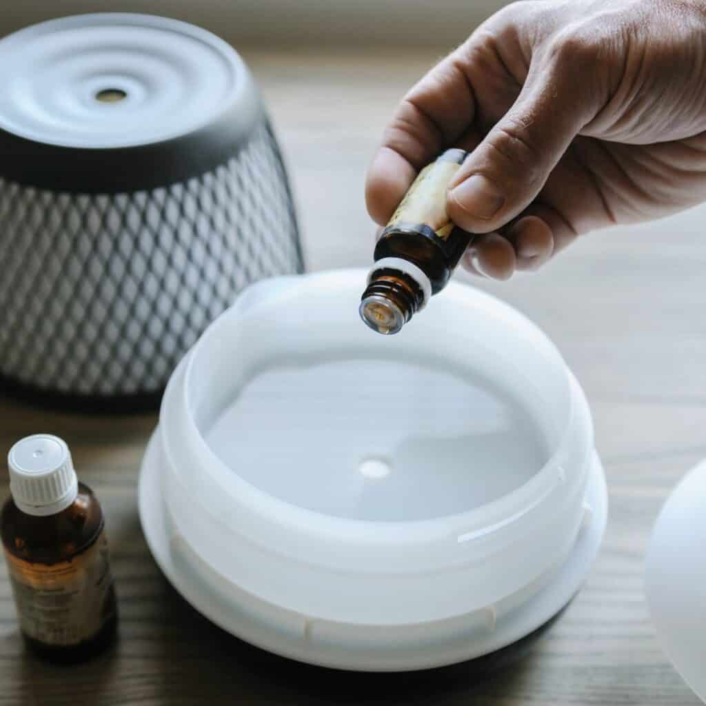 hand adding essential oils to a diffuser