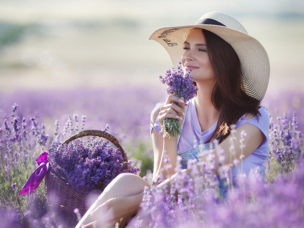 woman sitting in lavender field smelling flowers