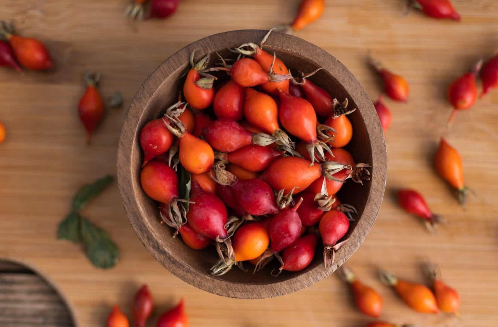 A bowl of rosehip on a wooden table.