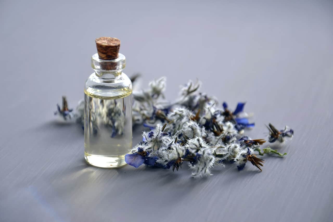 Essential oil bottle next to lavender sprig.