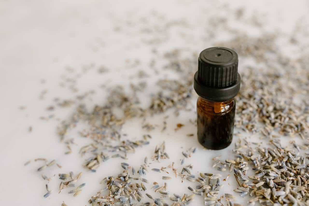 Essential oil bottle on white table with seeds.