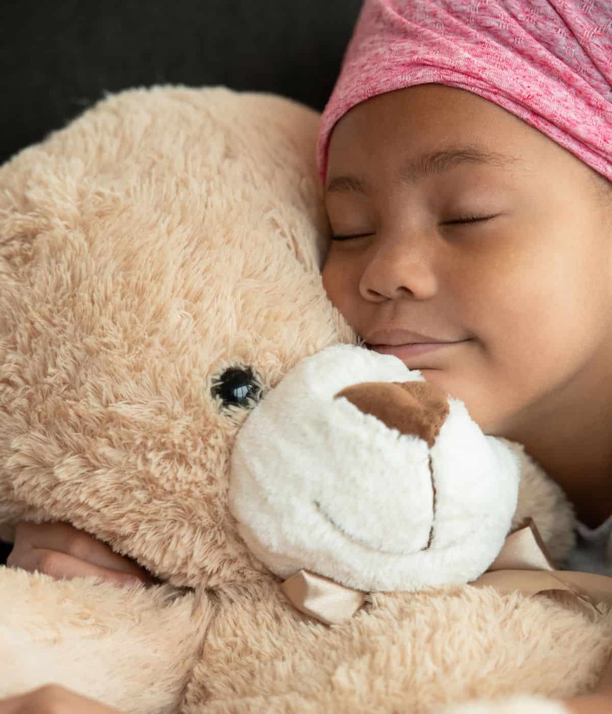 Little girl sleeping with a teddy bear stuffed animal.