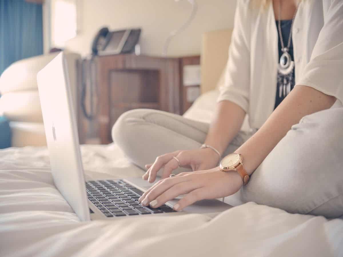 Woman sitting in bed at laptop typing.