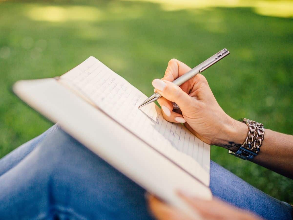 Woman writing in a book outside.