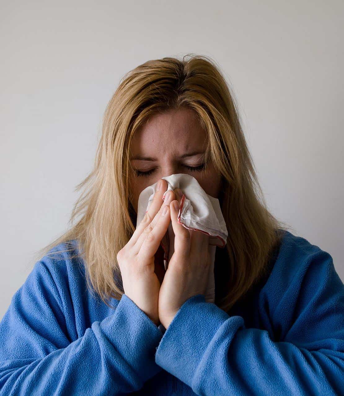 A sick woman blowing her nose.