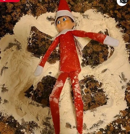 Elf on the shelf making a snow angel in flour.